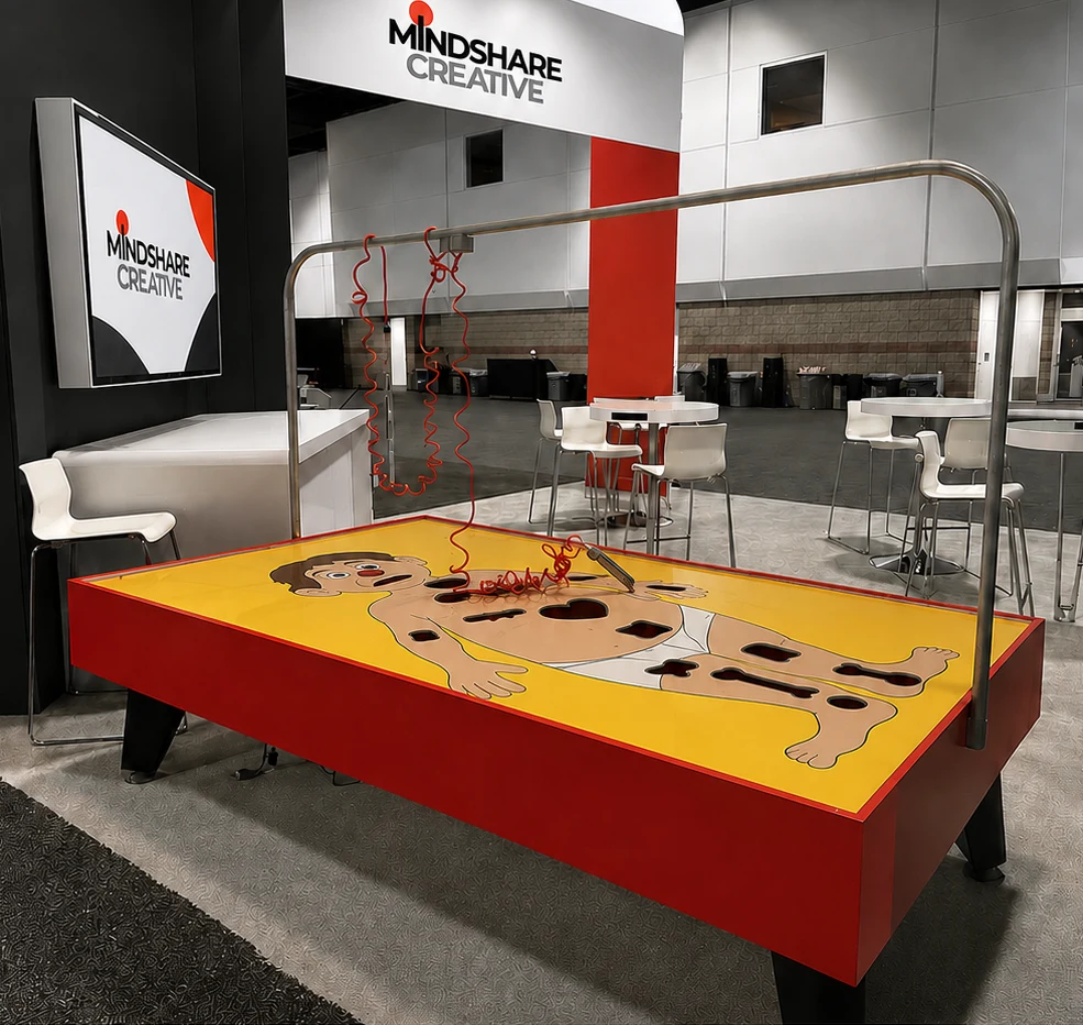 Mindshare Creative booth featuring a custom oversized interactive Operation-style game